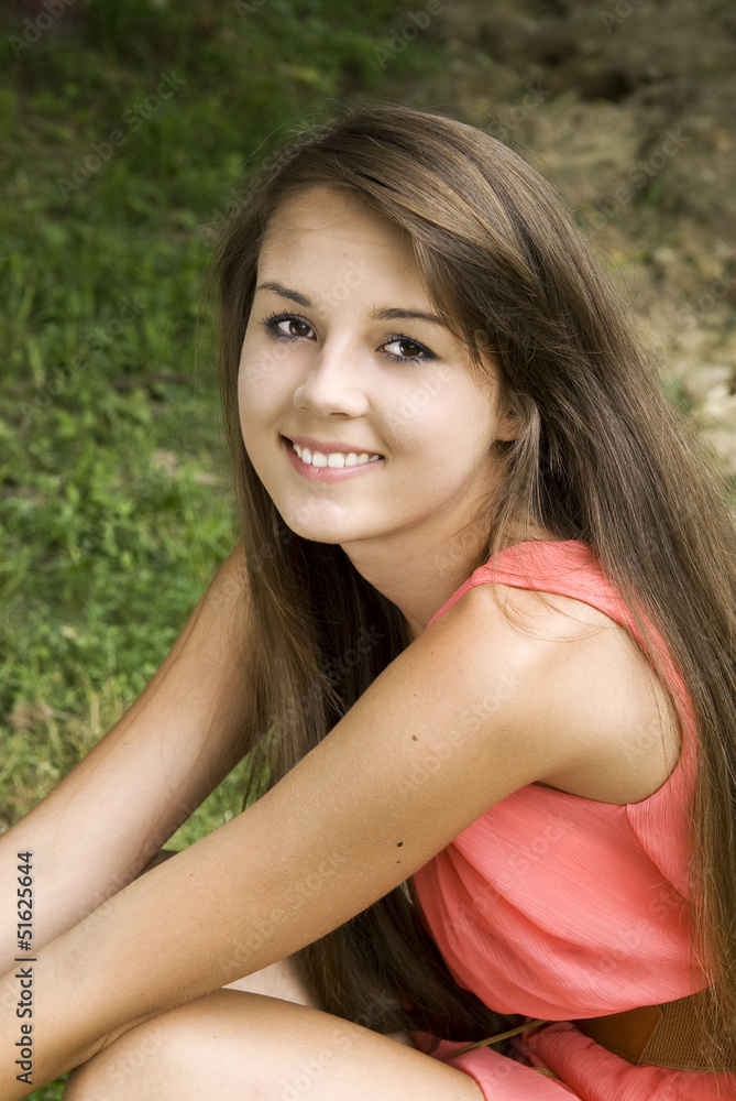 Naklejka premium Pretty happy young brunette posing outdoors .