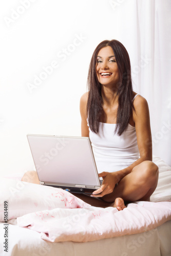 Young woman on bed using laptop