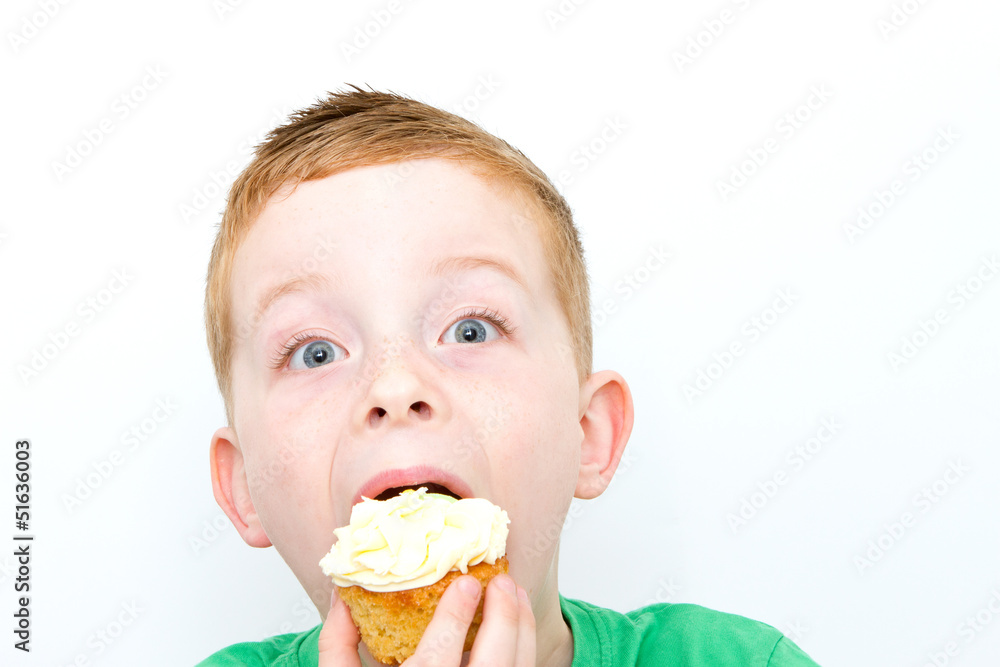 handsome little boy eating a fresh cream cup cake with messy fac handsome little boy eating a fresh cream cup cake with messy fac