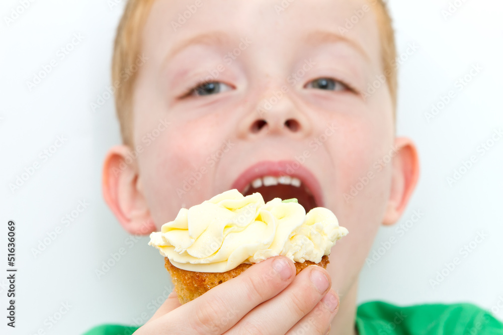 handsome little boy eating a fresh cream cup cake with messy fac handsome little boy eating a fresh cream cup cake with messy fac