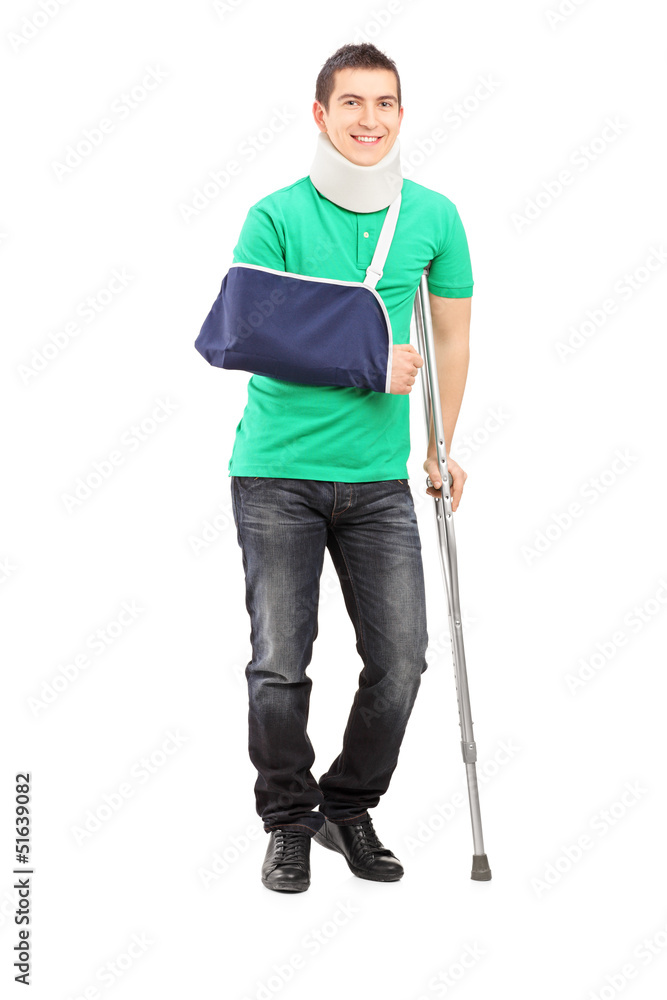 Full length portrait of a smiling male with broken arm and crutc Full length portrait of a smiling male with broken arm and crutc