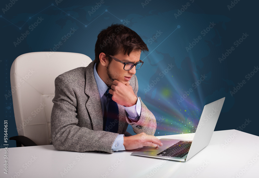 Handsome man sitting at desk and typing on laptop with abstract Handsome man sitting at desk and typing on laptop with abstract