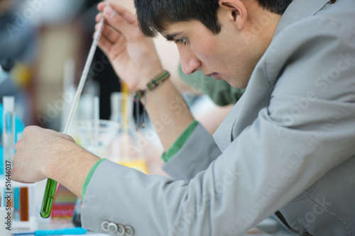 Male student with group of classmates on background working at t photo