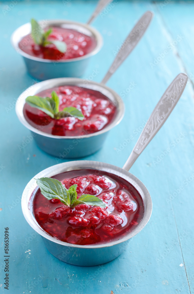 Raspberry sauсe with mint leaf on blue wooden background Raspberry sauсe with mint leaf on blue wooden background