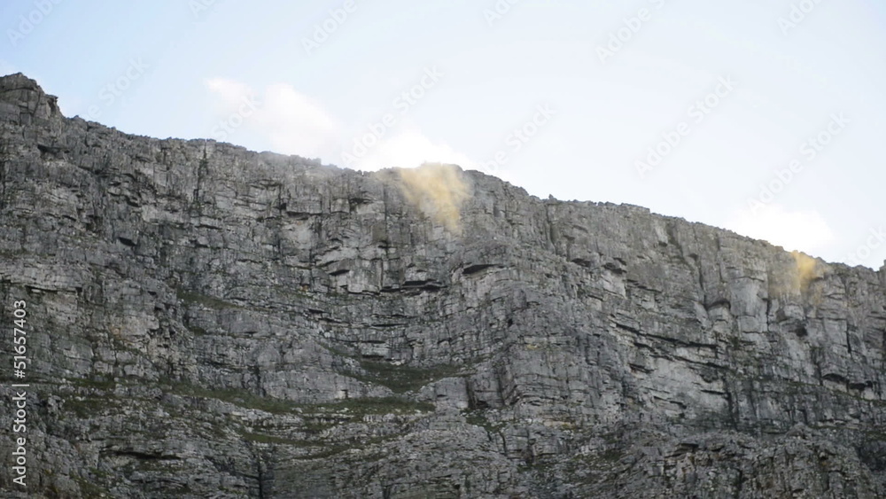 White clouds hanging above grey rocky part of Table Mountain White clouds hanging above grey rocky part of Table Mountain