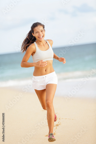 Runner woman running on beach smiling happy