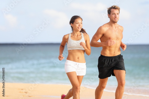 Couple running - sport runners jogging on beach
