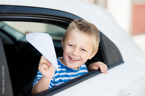 kleiner junge mit papierflieger im auto