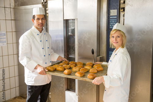 Bakers with tablet of bread in bakery or bakehouse