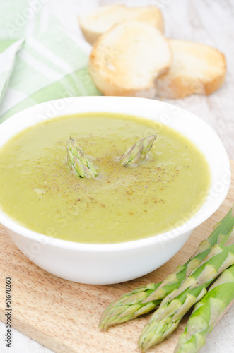 cream soup of asparagus and green peas in a bowl with toast
