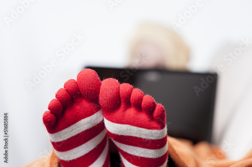 women with funny socks surfing internet on sofa