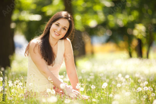 Cute woman rest in the park with dandelions