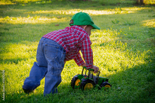 Young Boy Pushing Toy Tractor in Grass