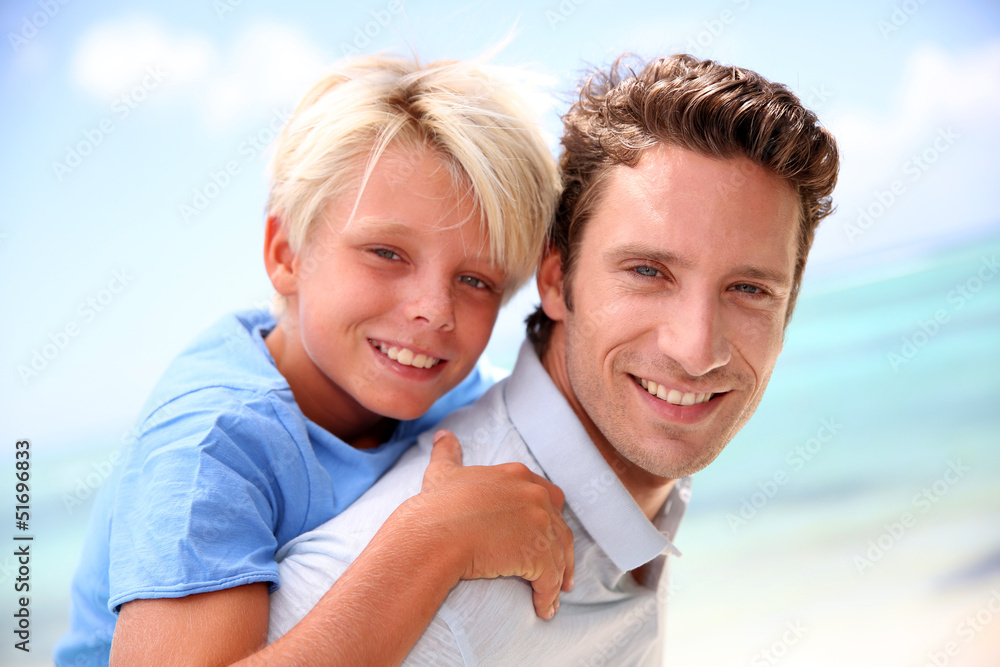 Daddy giving piggyback ride to son by the beach Daddy giving piggyback ride to son by the beach