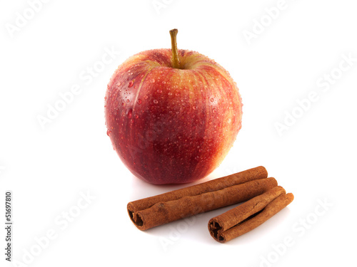 Isolated wet red apple with cinnamon pods