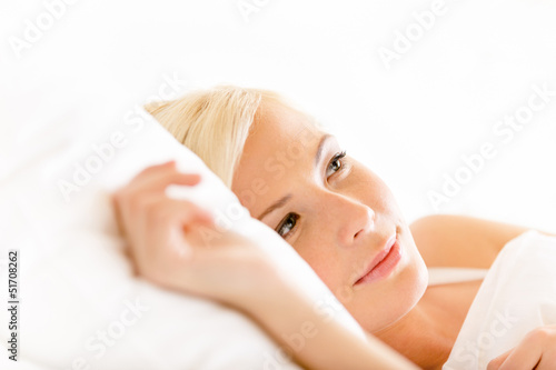 Close up shot of lying in bed woman on white pillow