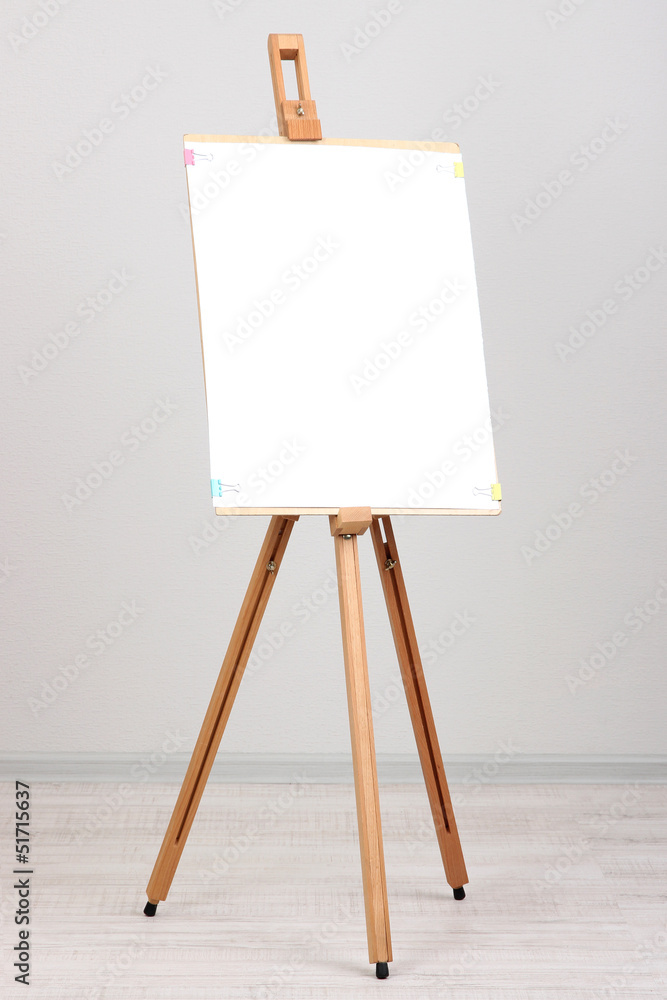 Wooden easel with clean paper in room Wooden easel with clean paper in room