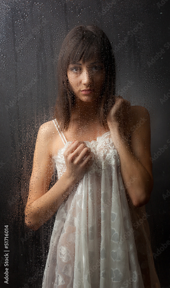 Obraz premium The brunette for a wet glass on a black background.