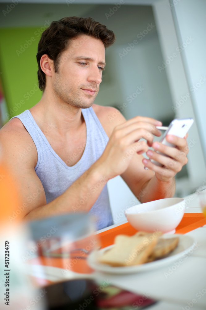 Man using smartphone while having breakfast Man using smartphone while having breakfast