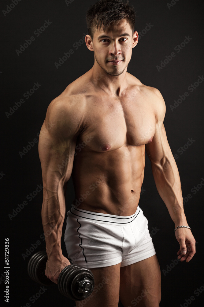 Muscular young man with a dumbbell over white Muscular young man with a dumbbell over white