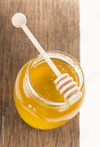 Honey in bank on wooden boards isolated by the white