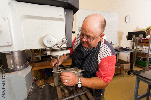 senior male artisan working on industrial drilling machine photo