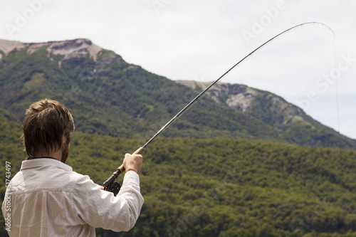 Hombre pescando en paisaje de montañas. © simonlaprida