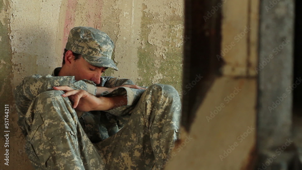 Distraught soldier sitting against concrete wall Stock Video | Adobe Stock