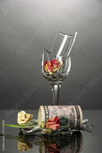 Broken wineglass and money on grey background