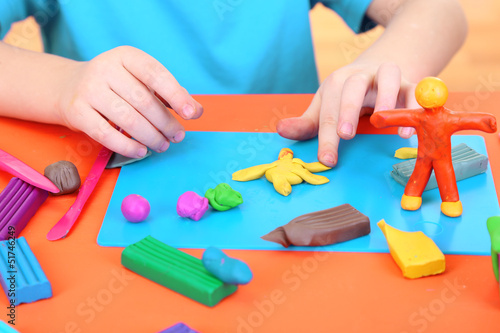 Child moulds from plasticine on table photo