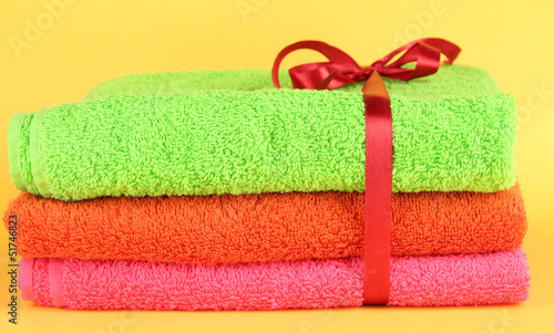 Towels tied with ribbon on yellow background © Africa Studio
