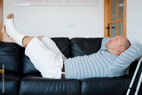 mann mit gips liegt auf dem sofa photo