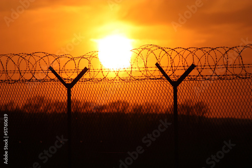 Security fence at sunset with barbed wire