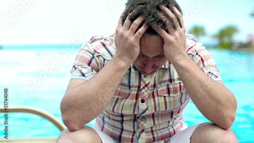 Sad man sitting by the swimming pool, steadycam shot