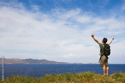 Young tourist with backpack enjoying sea view from top of a hill