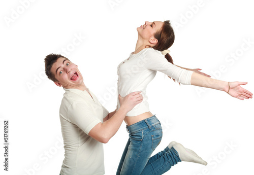 Young couple, guy with jumping up girl, studio, isolated