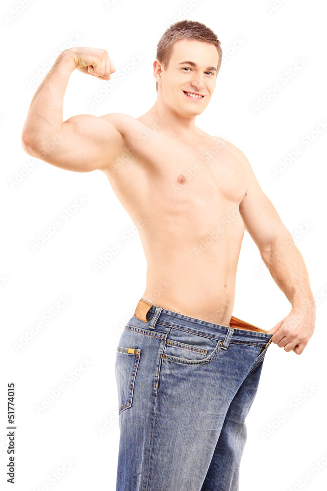Fototapeta premium Fit muscular man in a big pair of jeans showing his biceps