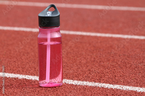 a close up shot of a water bottle on a track outside.
