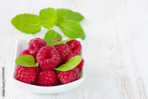 raspberries with mint in white bowl