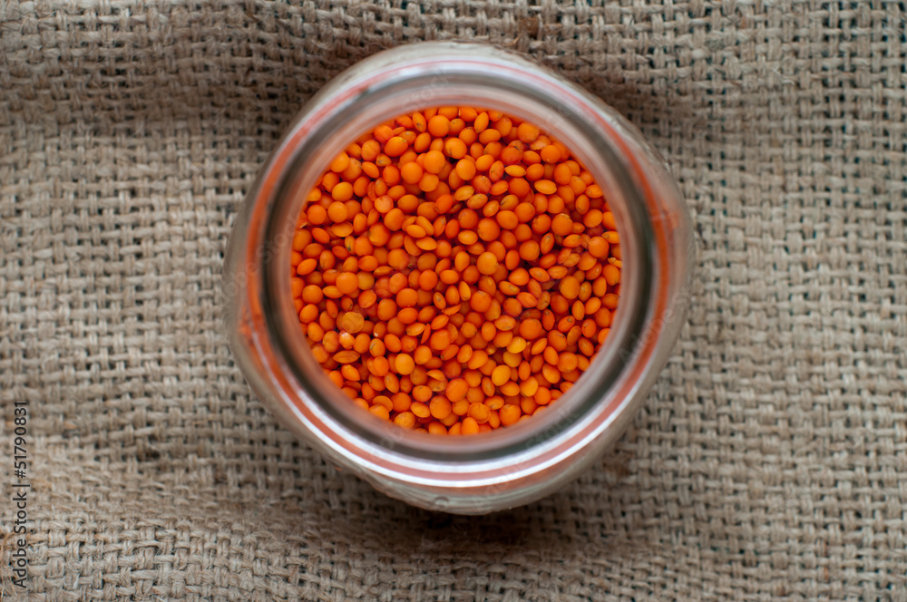 Red lentils in a glass jar on a sackcloth