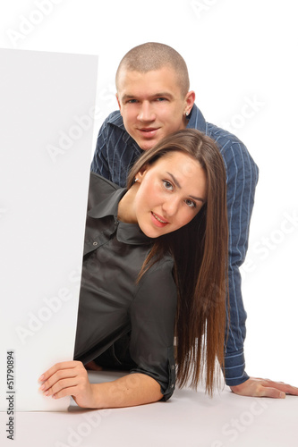 A couple lying behind a blank, isolated on white background