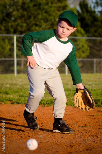Young child fielding ball while playing baseball