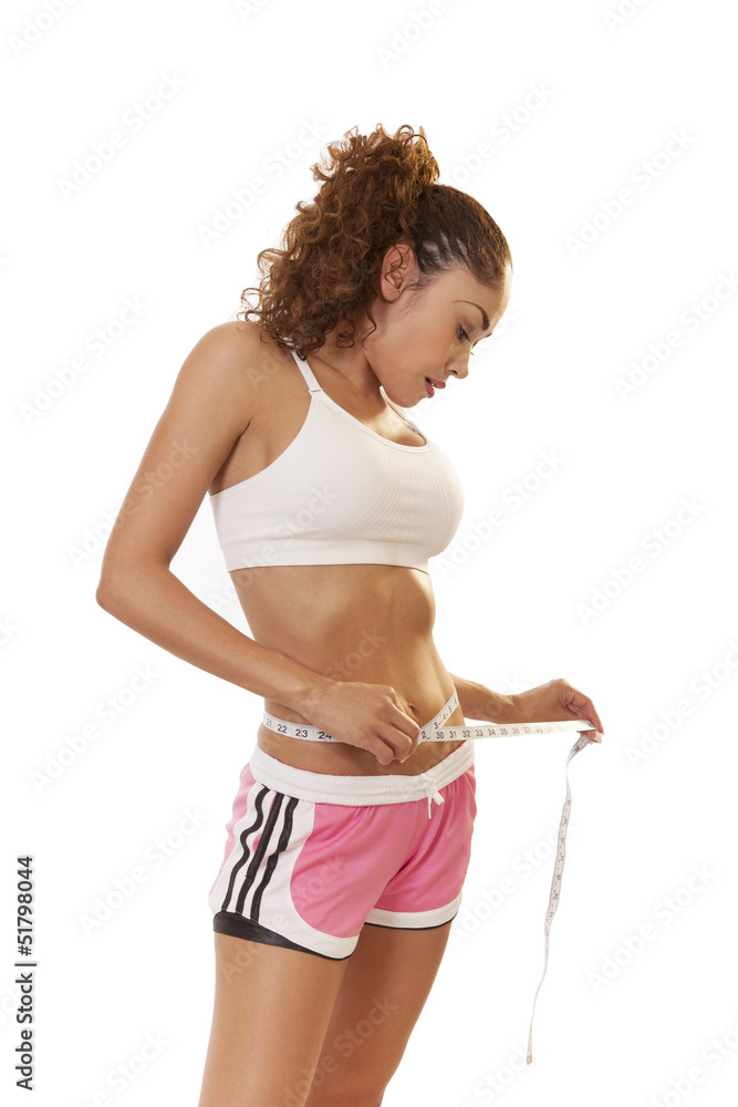 Fit, petite woman with toned abs measures her waist. Stock Photo