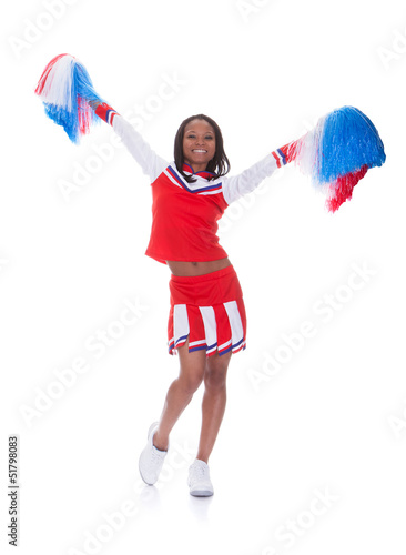 Smiling beautiful cheerleader with pompoms. © Andrey Popov