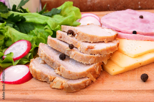 Pork, ham, cheese and vegetables on a wooden board