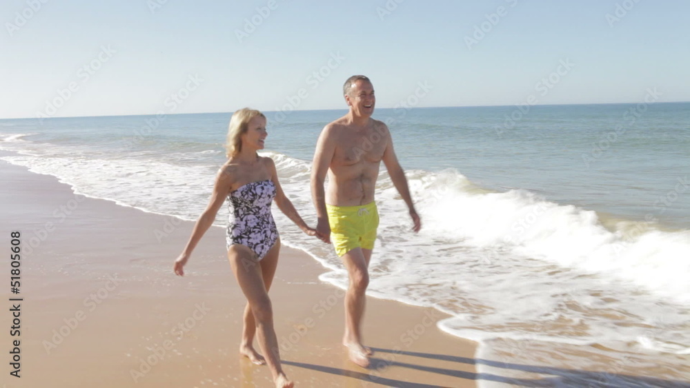 Senior Couple Holding Hands Walking Along Beach Senior Couple Holding Hands Walking Along Beach