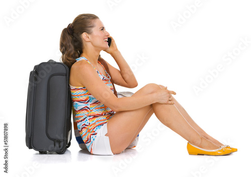 Young tourist woman with wheel bag sitting on floor