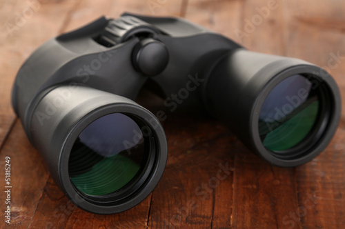 Black modern binoculars on wooden background