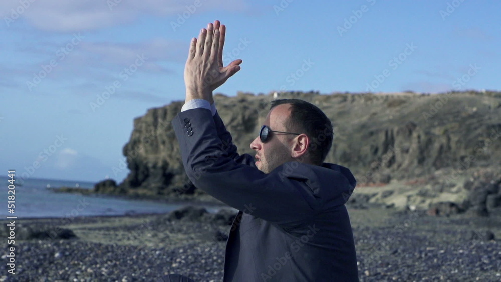 Businessman meditating on a sunny beach in the morning, slow mot Businessman meditating on a sunny beach in the morning, slow mot