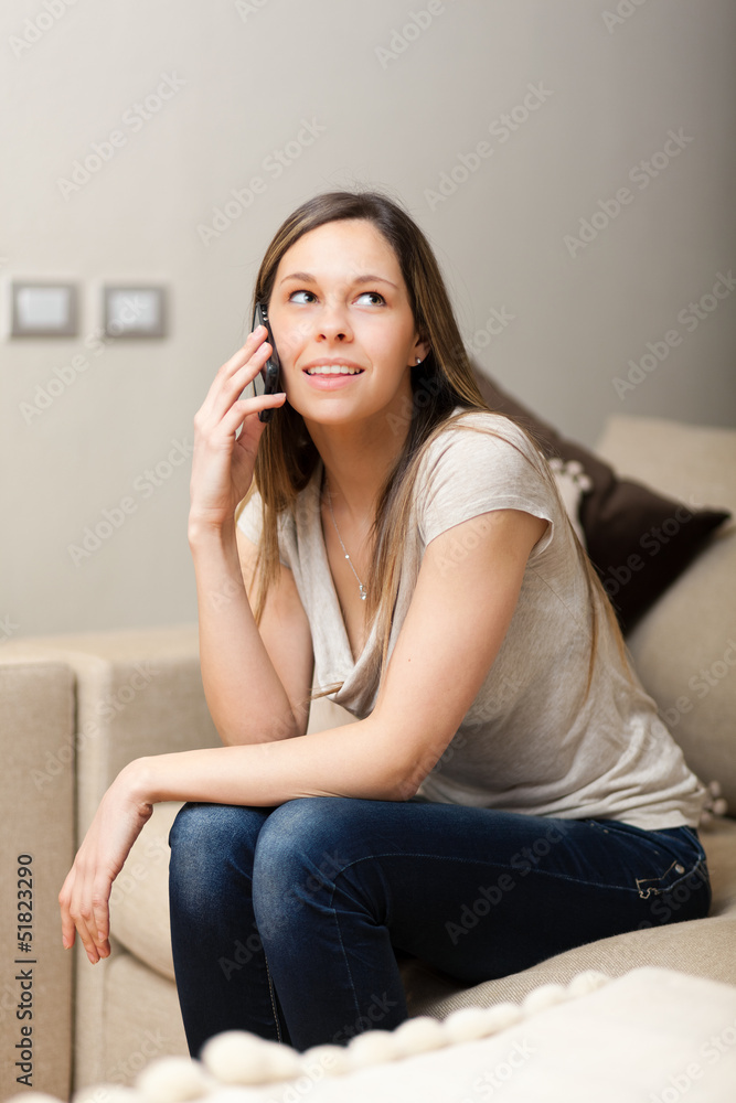 Woman using a cell phone while relaxing on a couch Woman using a cell phone while relaxing on a couch
